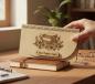 Preview: Holz-Umschlag aus hellem Birkensperrholz mit gelaserter Gravur A New Chapter Begins. Der Umschlag liegt dekorativ arrangiert, die natürliche Maserung und feinen Lasercut‑Details sind gut sichtbar. Ideal als Geschenkverpackung für Geld oder Gutscheine zu S